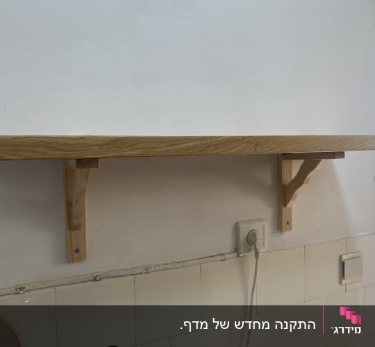 מדף עץ מותקן על קיר עם תומכים
